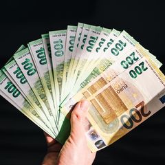 Eine Hand hält aufgefächerte Geldscheine