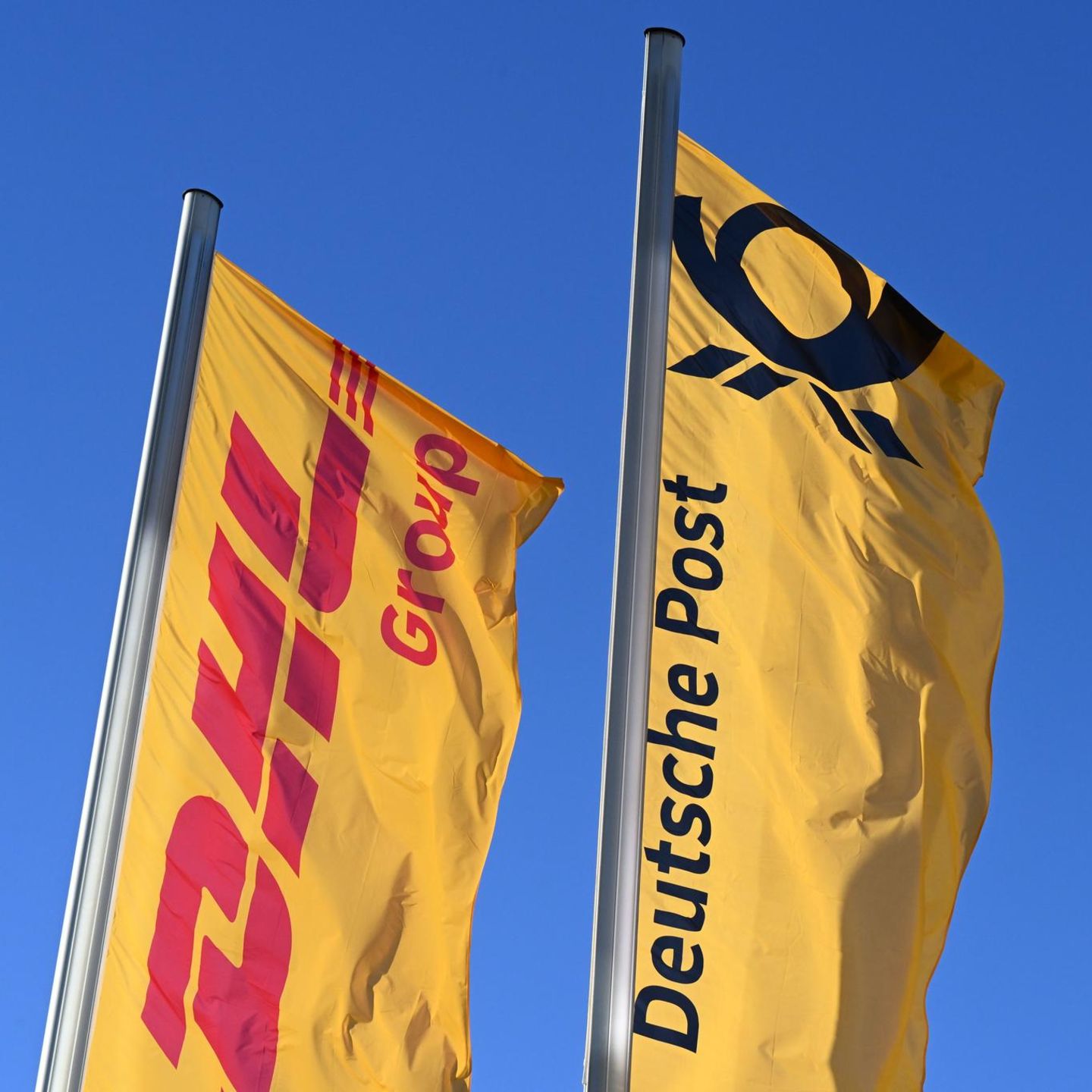 Fahnen des Logistikkonzerns DHL und seiner Brieftochter Deutsche Post wehen vor der Konzernzentrale an Masten