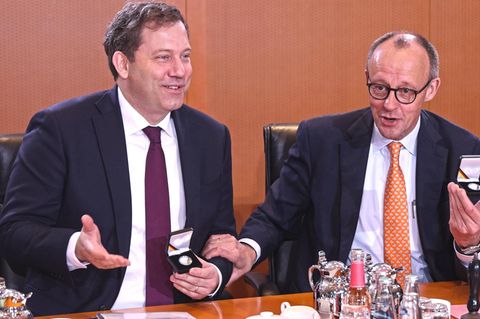 Lars Klingbeil und Friedrich Merz sitzen am Kabinettstisch und lachen
