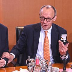Lars Klingbeil und Friedrich Merz sitzen am Kabinettstisch und lachen