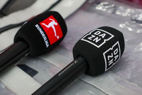 Mikrofone mit den Logos von Bundesliga und Dazn liegen auf einer Box