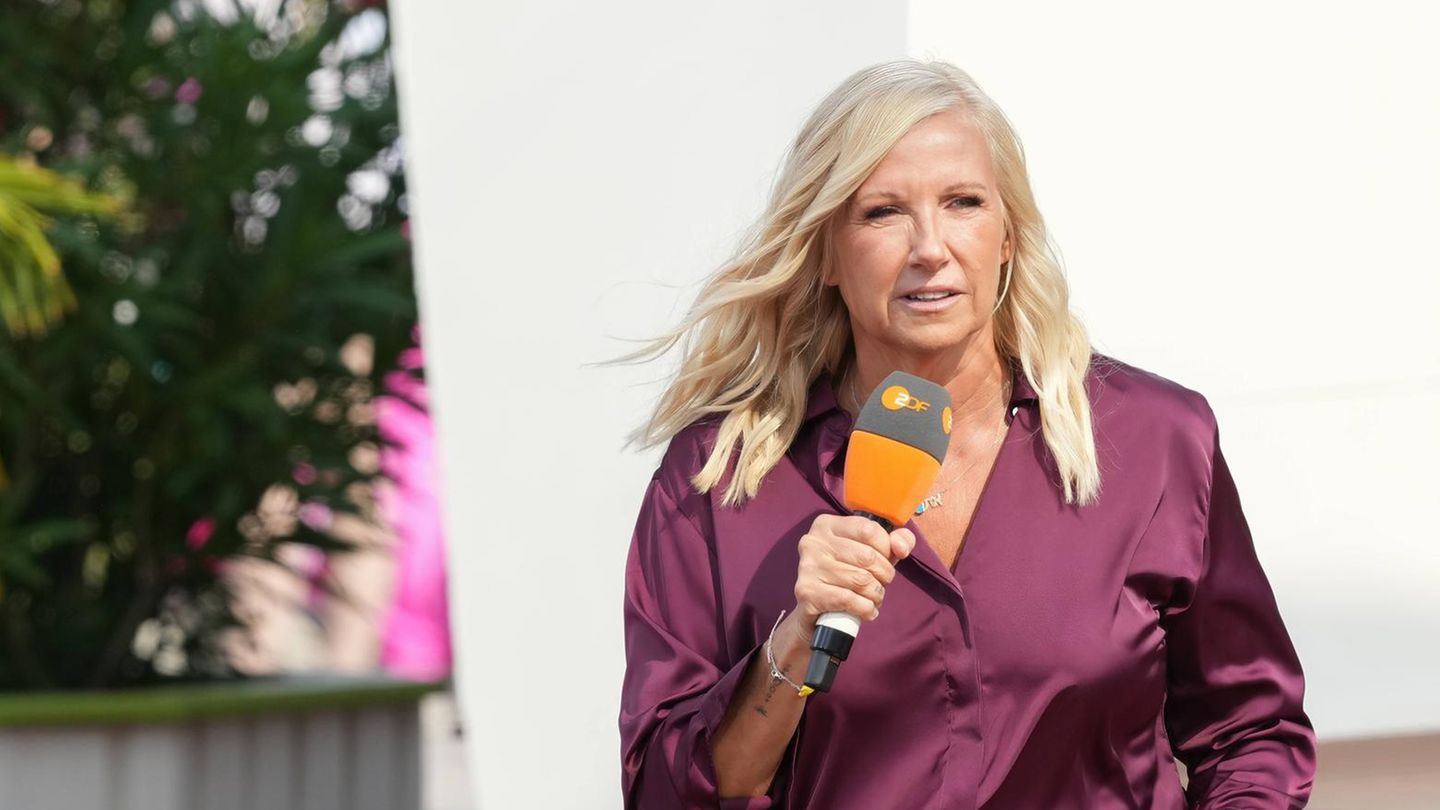 Andrea Kiewel trägt eine Bluse und offene, gewellte Haare und hält ein Mikrofon in der Hand