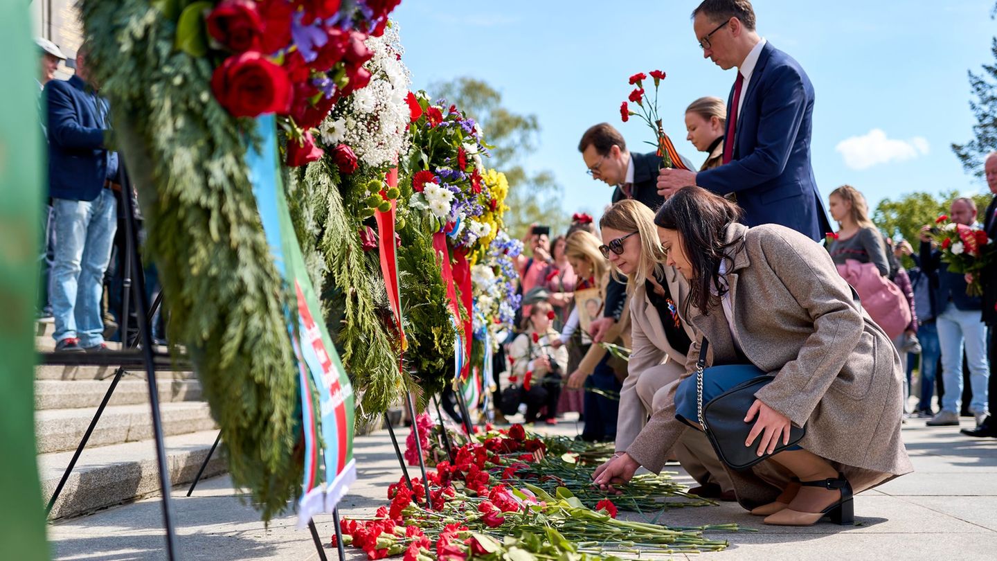Menschen haben rote Blumen niedergelegt. Foto: Michael Ukas/dpa