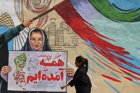 Iranerin vor politischem Wandgemälde in Teheran