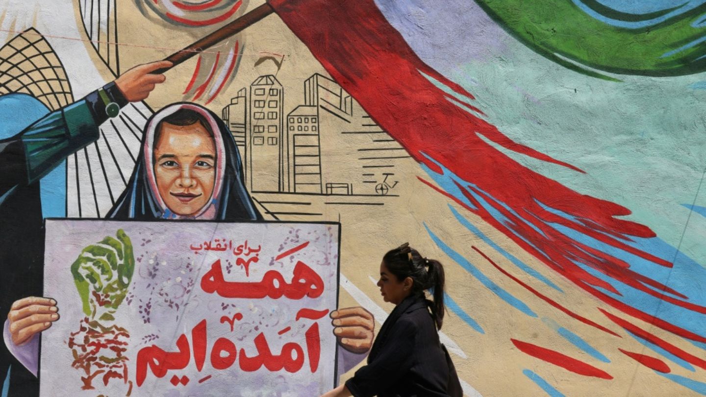 Iranerin vor politischem Wandgemälde in Teheran