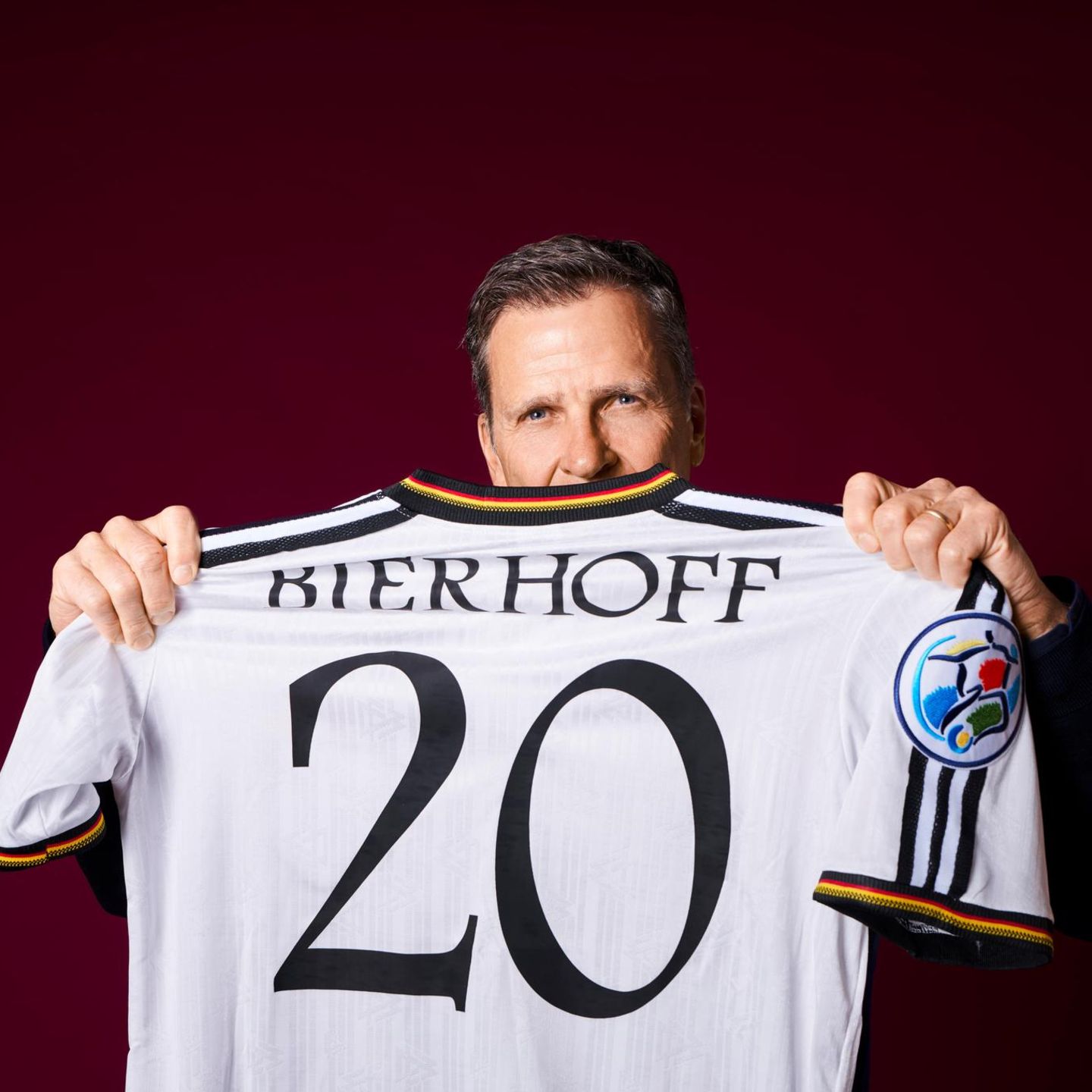 Oliver Bierhoff hält ein altes Trikot von der EM 1996 in die Kamera