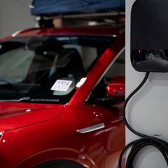 Ein rotes E-Auto ist an einer Wallbox angeschlossen
