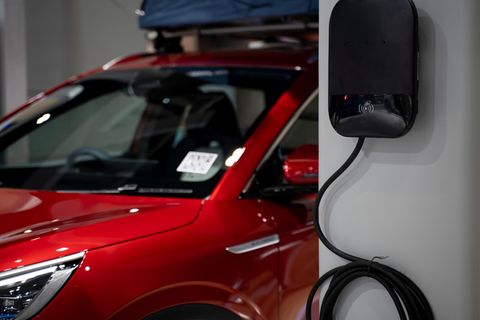 Ein rotes E-Auto ist an einer Wallbox angeschlossen