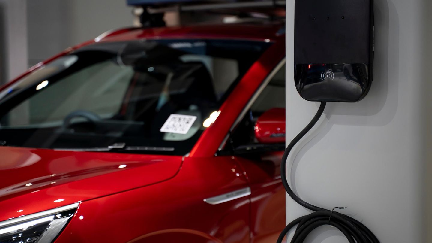 Ein rotes E-Auto ist an einer Wallbox angeschlossen