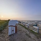 Strand mit Strandkörben im Gegenlicht der untergehenden Sonne im Ortsteil Hooksiel