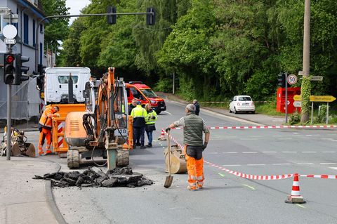 Einsatzkräfte arbeiten auf einer Straße. In Wuppertal hat die Feuerwehr wegen Einsturzgefahr eine vielbefahrene Kreuzung gesperr