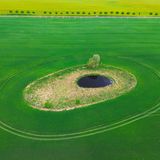 Sieversdorf, Deutschland. Man könnte meinen, es sei ein Auge, das dort aus dem Acker in den Himmel blickt. Doch es handelt sich um ein sogenanntes „Soll“, eine kleine Vertiefung mit einem Wasserloch. Solche „Sölle“ sind häufig als Folge von Eiszeiten im nordostdeutschen Raum entstanden. Heute bilden sie ökologisch wertvolle Inseln in landwirtschaftlich stark genutzten Flächen.