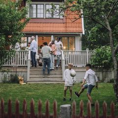 Eine Familie versammelt sich auf der Terasse vor einem Haus (Symbolbild Erbe)
