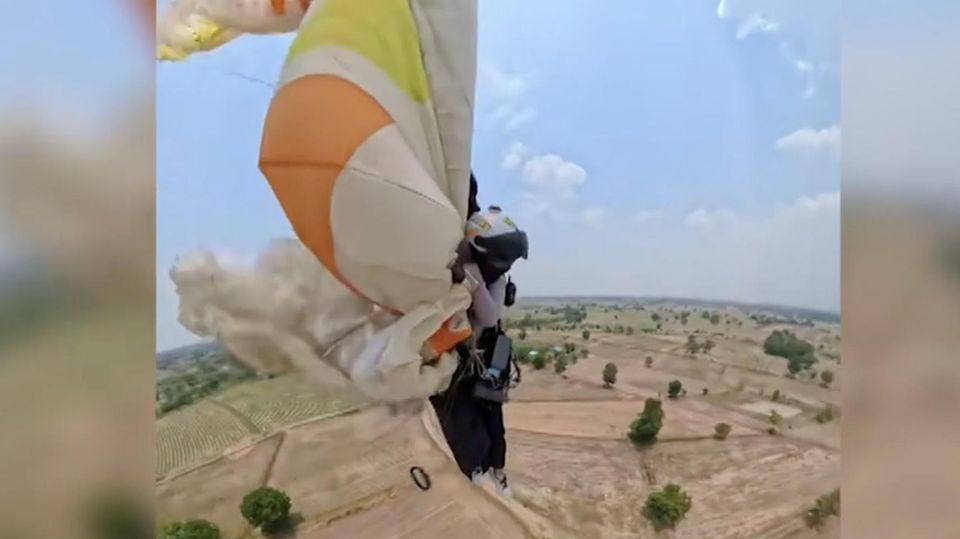 Eine Paragliderin rettet sich mit ihrem defekten Gleitschirm im Flug.