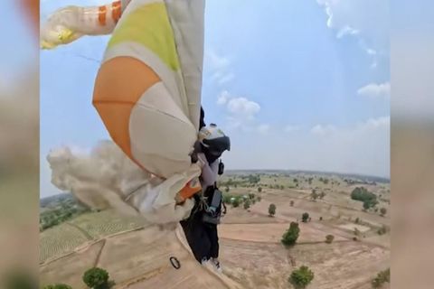 Eine Paragliderin rettet sich mit ihrem defekten Gleitschirm im Flug.