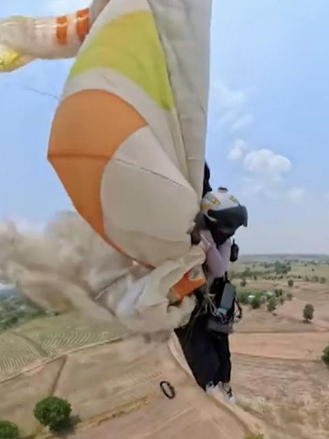 Eine Paragliderin rettet sich mit ihrem defekten Gleitschirm im Flug.