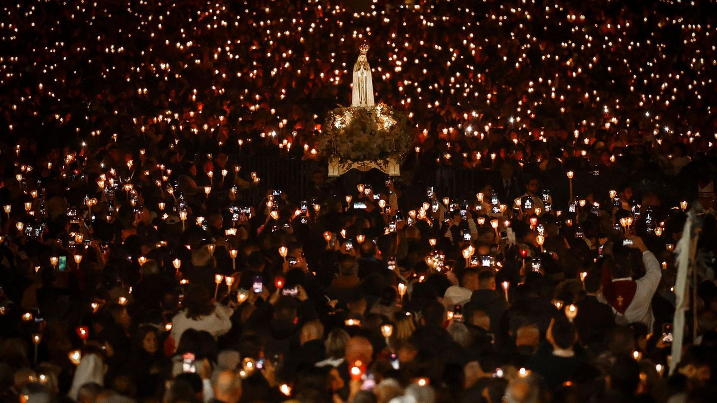 Fatima, Portugal. Am späten Abend wird während der Lichterprozession am Heiligtum von Fátima in Zentralportugal ein Festwagen mit einer Statue der Muttergottes von Fátima getragen. Tausende Pilger strömten zum Heiligtum, um den Jahrestag des Wunders von Fátima zu feiern. Bei diesem Wunder hatten drei Hirtenkinder im Mai 1917 angegeben, die Jungfrau Maria gesehen zu haben.