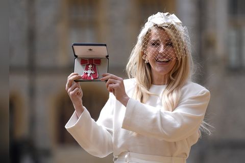 Ellie Goulding zeigt stolz ihren MBE-Orden.