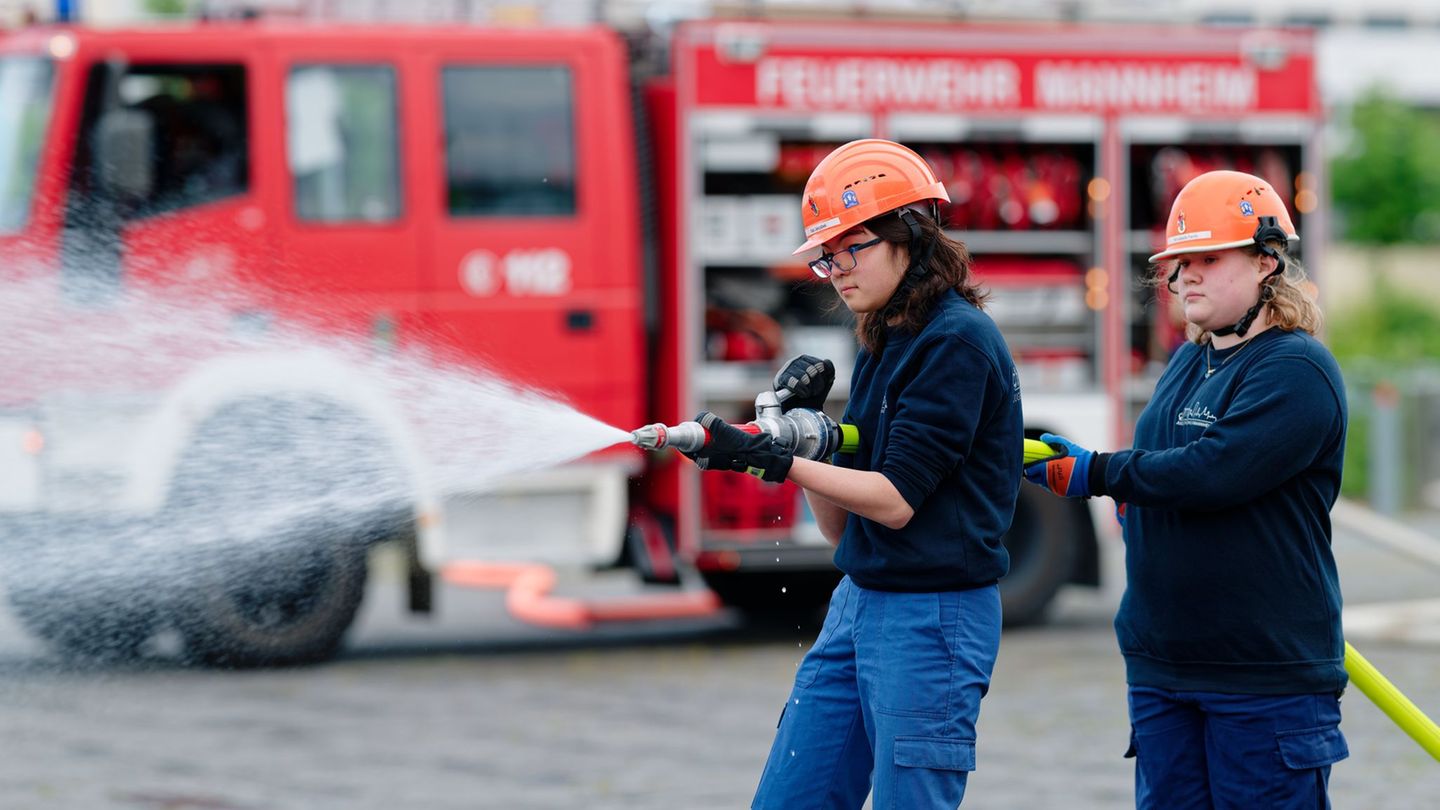 Ilias (links) und Annabella, Mitglieder der Jugendfeuerwehr in Mannheim, halten bei einer Übung einen Feuerwehrschlauch in den H