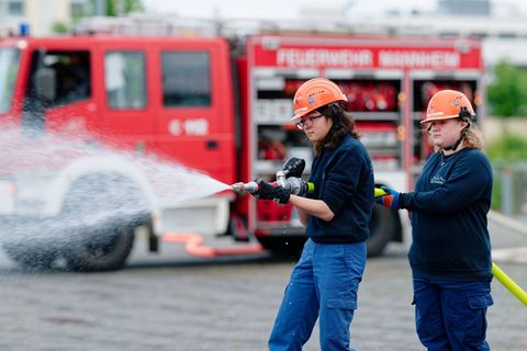 Ilias (links) und Annabella, Mitglieder der Jugendfeuerwehr in Mannheim, halten bei einer Übung einen Feuerwehrschlauch in den H