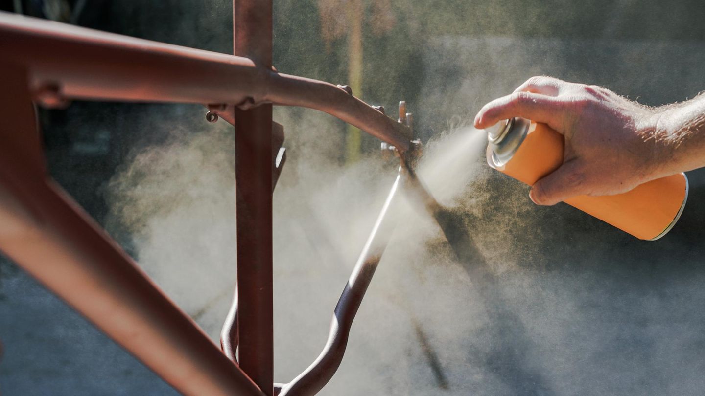 Junger Mann lackiert Fahrrad in der Garage