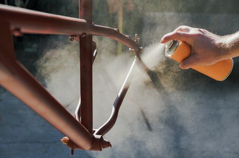Junger Mann lackiert Fahrrad in der Garage