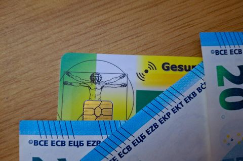 Krankenversicherungskarten und Euro-Scheine liegen auf einem Tisch (Symbolbild)