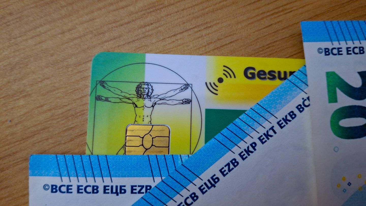 Krankenversicherungskarten und Euro-Scheine liegen auf einem Tisch (Symbolbild)