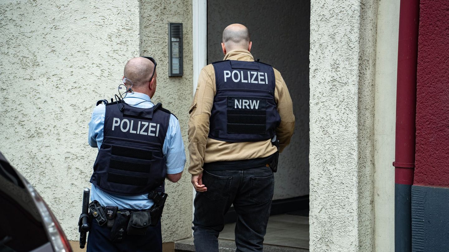 Polizisten stehen vor einem Hauseingang. Ein mutmaßlich der "Reichsbürger"-Szene angehörender Mann ist in Wuppertal von der Poli