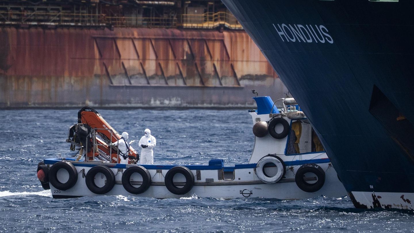 Hantavirus: Die Hondius liegt im Hafen in Teneriffa vor Anker, davor stehen Menschen in Schutzanzügen auf einem kleineren Schiff