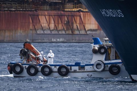 Hantavirus: Die Hondius liegt im Hafen in Teneriffa vor Anker, davor stehen Menschen in Schutzanzügen auf einem kleineren Schiff