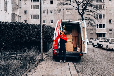 Ein Paketlieferant an seinem vollgepackten Auto