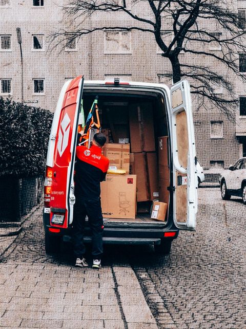 Ein Paketlieferant an seinem vollgepackten Auto