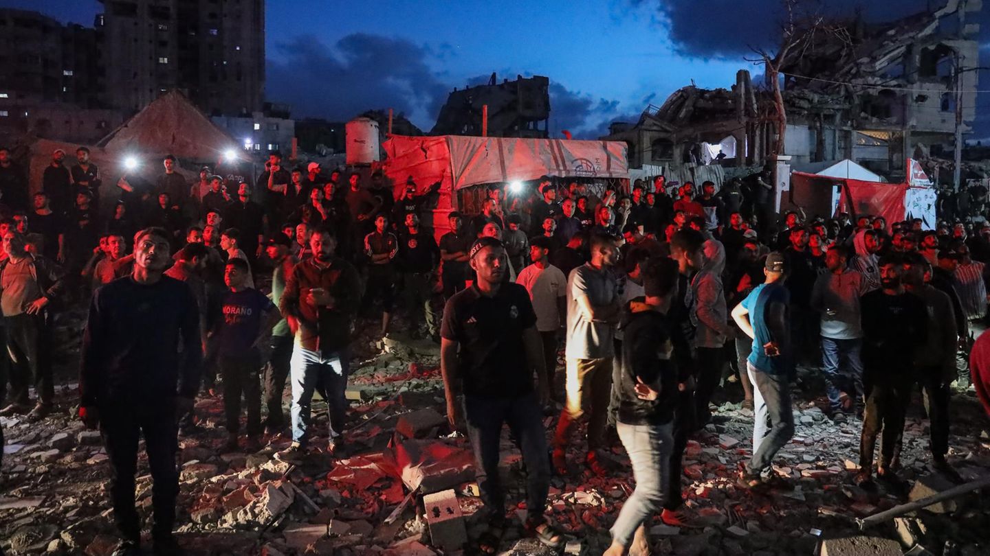 Menschen im Gaza-Streifen schauen zu einem brennenden Gebäude hinauf