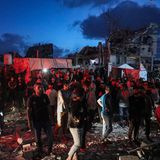 Menschen im Gaza-Streifen schauen zu einem brennenden Gebäude hinauf