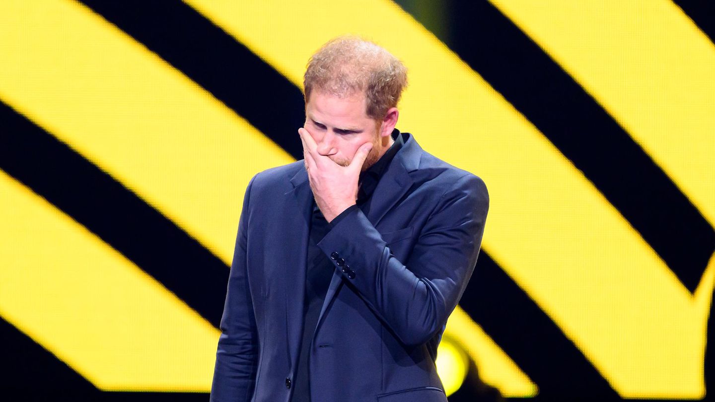 Prinz Harry hält sich eine Hand vor den Mund