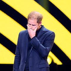 Prinz Harry hält sich eine Hand vor den Mund