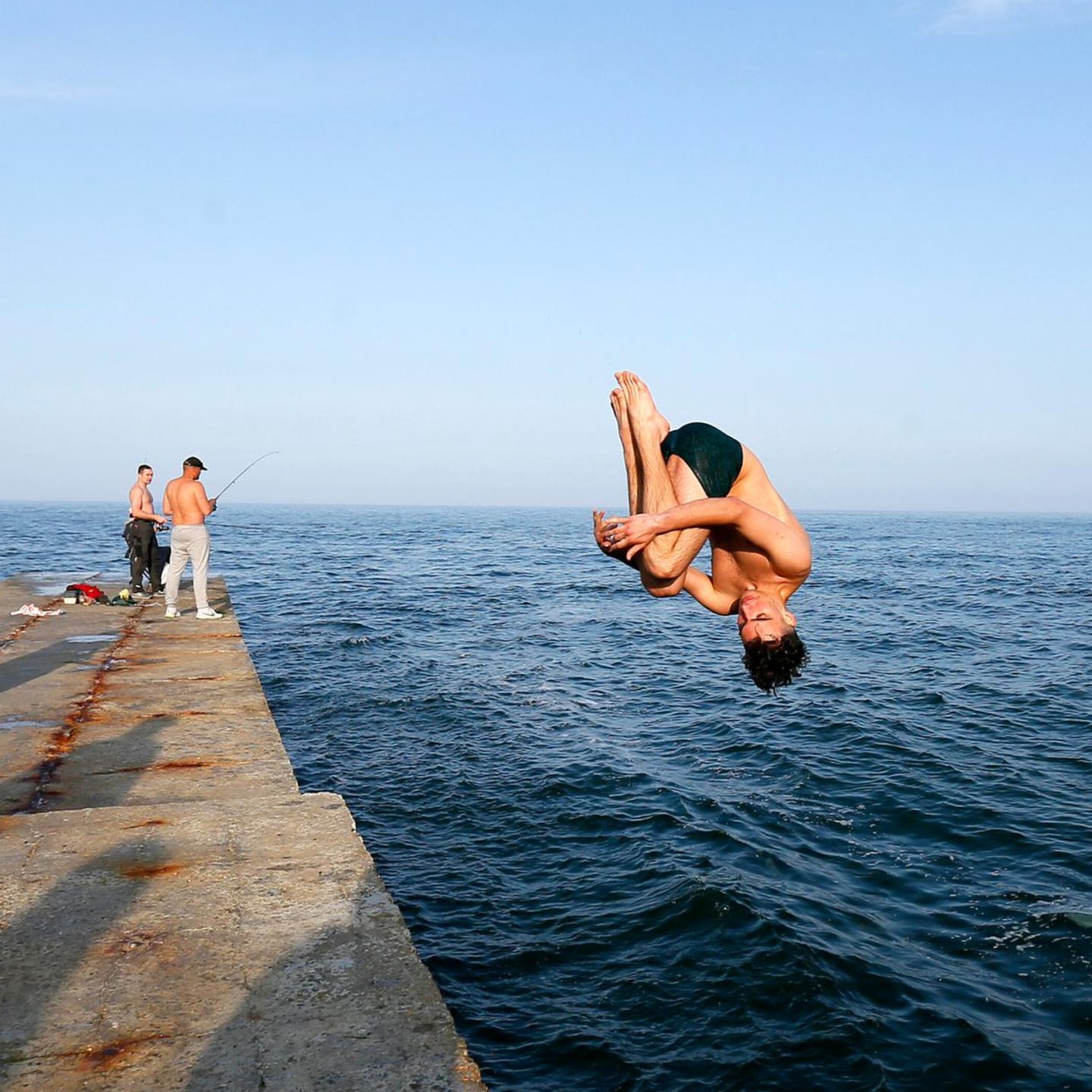 Ein Mann springt in einem Salto ins Meer in Odessa
