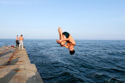 Ein Mann springt in einem Salto ins Meer in Odessa