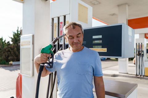 Symbolbild Tankrabatt? Ein Mann hält sich an der Tankstelle eine Zapfpistole an die Schläfe