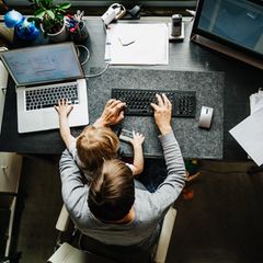 Arbeitszeitgesetz: Mann sitzt mit Kind auf dem Schoß im Homeoffice