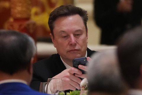 Elon Musk schaut auf sein Handy