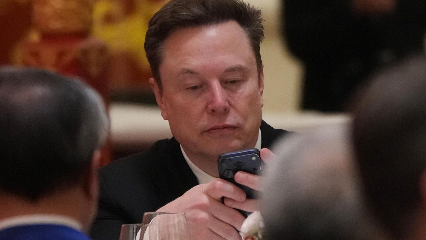 Elon Musk schaut auf sein Handy