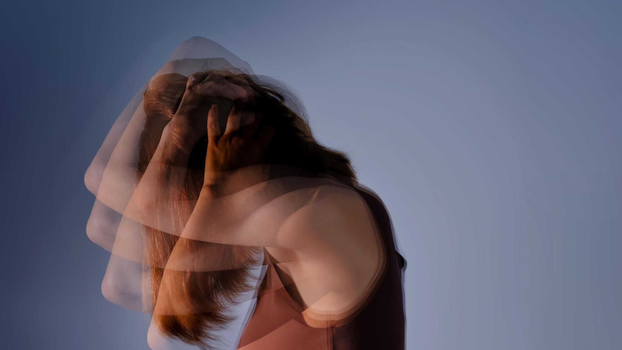 Thema Kopfschmerz: Ein Frau hält sich die Arme über den Kopf