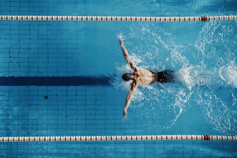 Vogelperspektive auf einen Mann, der im Delfin-Stil schwimmt