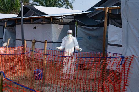 Ein Mensch im weißen Anzug steht vor einem Ebola-Behandlungszentrum im Kongo