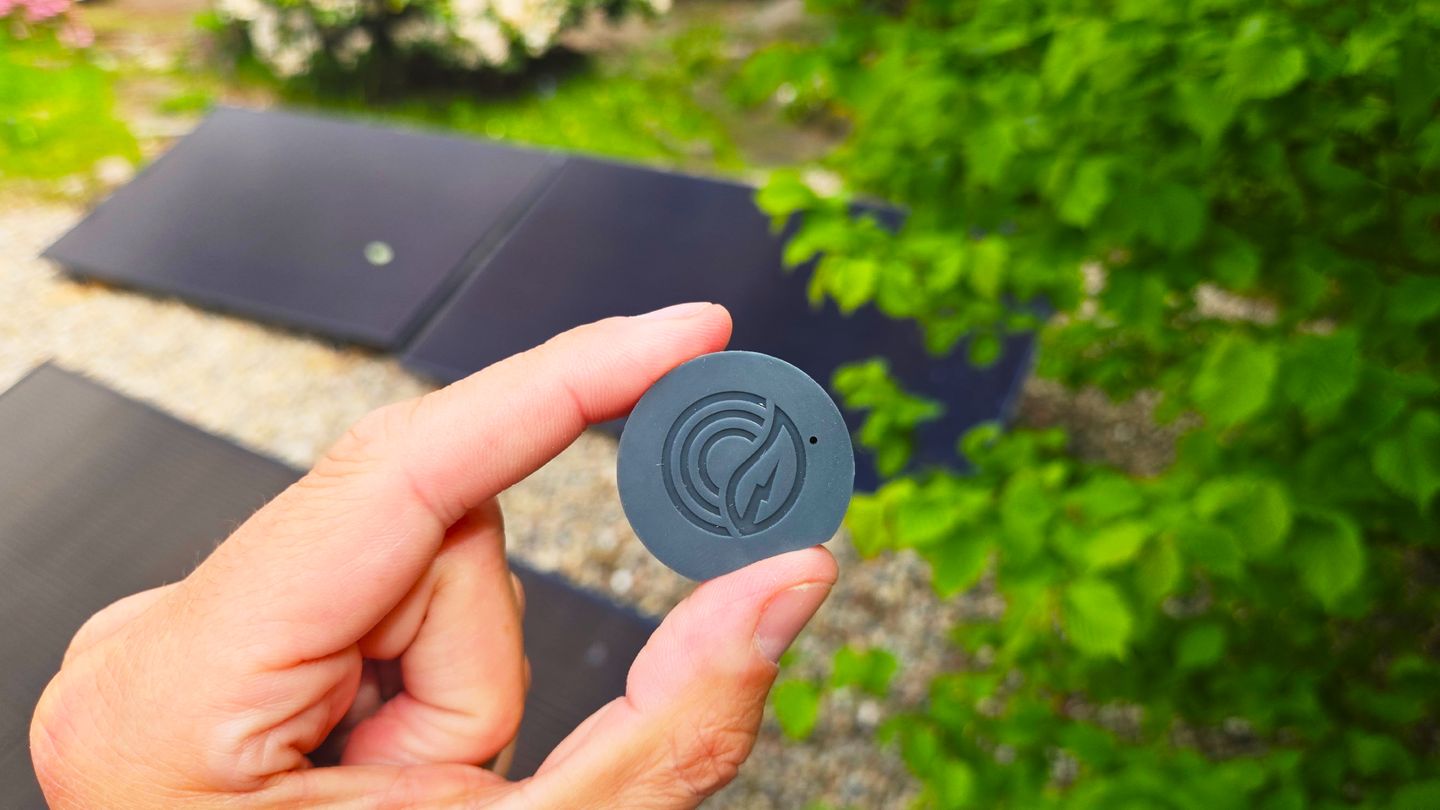Zwei Finger halten den schwarzen, runden PowerTracker IR von Solakon