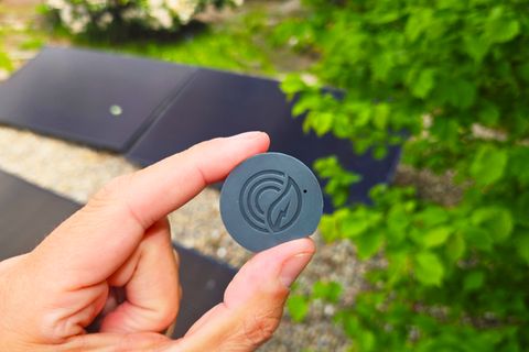 Zwei Finger halten den schwarzen, runden PowerTracker IR von Solakon