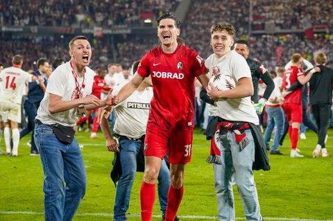 Fans des SC Freiburg stürmen nach dem Finaleinzug den Platz und halten Spieler Igor Matanović am Arm fest
