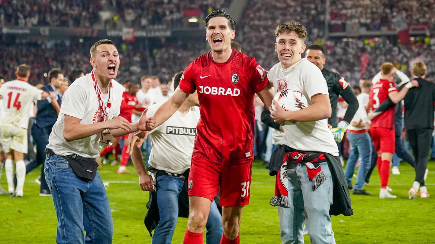Fans des SC Freiburg stürmen nach dem Finaleinzug den Platz und halten Spieler Igor Matanović am Arm fest